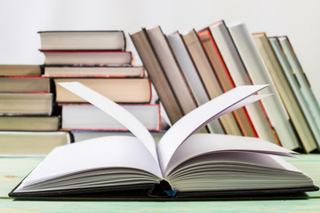 Open book and pile of various books on wooden background. With copy space for your text