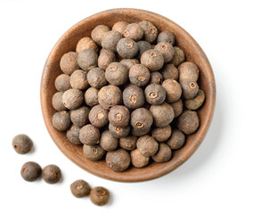 dried allspice in the wooden plate, isolated on white background, top view