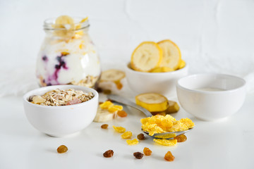 Breakfast in a jar: cereal, banana, fresh berries, granola, yogurt on a light background. The concept of healthy eating, high-carbon Breakfast.