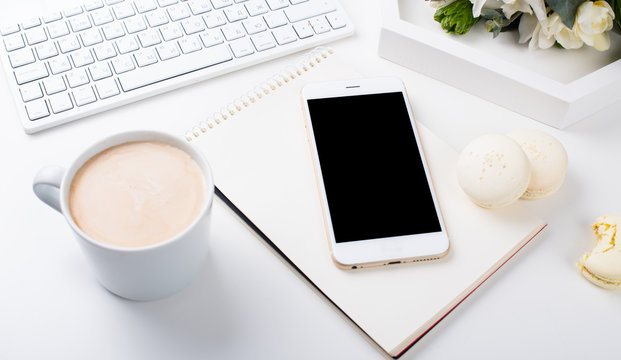 Lady bloggers work desk with fresh bouquet of flowers and macaro