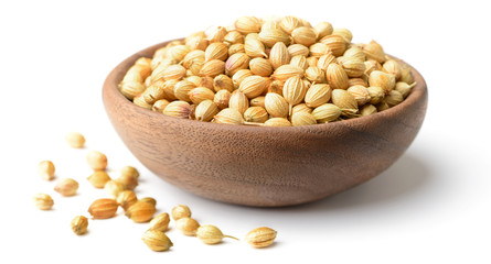 dried coriander seeds in the wooden plate, isolated on white