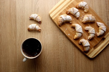 Little croissants and cup of coffee on rustic table background, copy space for text or object