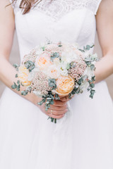 Beauty wedding bouquet of rose flowers and eucalyptus branches in bride's hands.