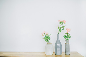 Pastel pink rose flowers in vases near white background.