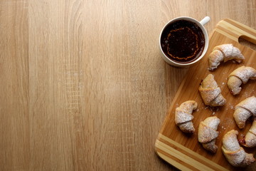 Fresh croissants and coffee for breakfast on rustic wooden   table, view from overhead, copy space for your text or object