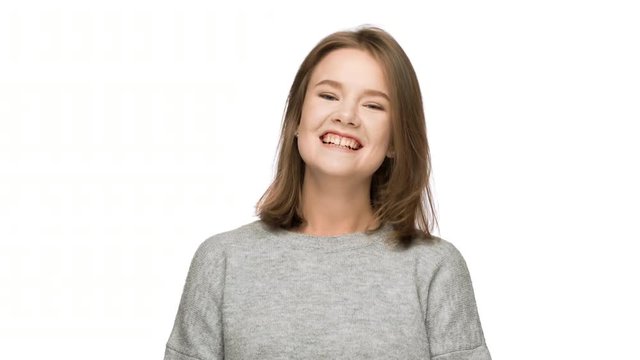 Portrait of positive woman 20s wearing basic clothing laughing or chuckling after amusing joke, isolated over white background in studio. Concept of emotions
