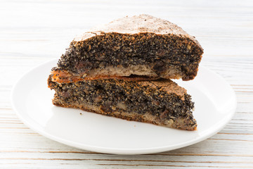 Two pieces of poppy seed cake on wooden white background 