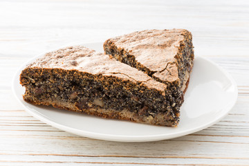 Two pieces of poppy seed cake on wooden white background 