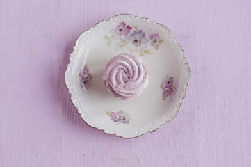 pink marshmallow flat lay on a lacy plate with flowers  and on wooden pink background.