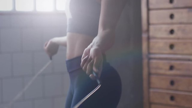 african american woman makes a jump rope routine in sunny loft for healthy life side view body closeup. Focus on hand