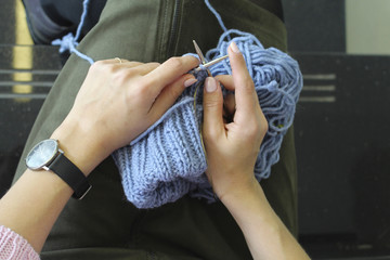 Female hands knit with knitting needles. Top view. Close-up.