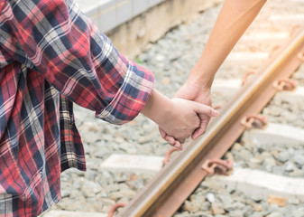 Man and woman walking hand in hand on railway.