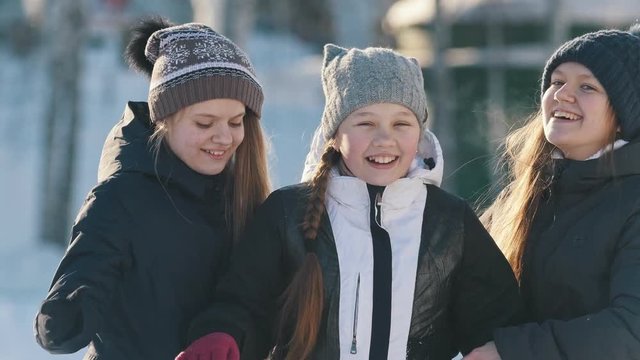 Portrait of three teenage girls posing, hugging and smiling in winter outside