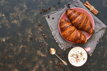 Breakfast with croissants and coffee on a rustic background. French pastry. The view from the top,space for text.