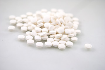 White round tablets close-up with reflection on white background