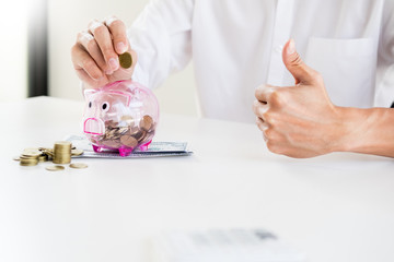 Obraz na płótnie Canvas Close up of Businessman putting coin into small piggy bank , The concept of saving money and investment