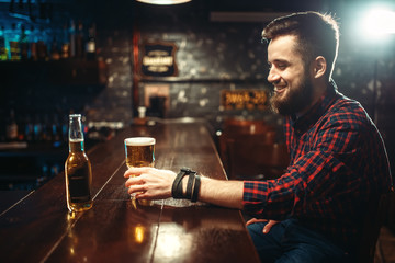 One bearded man drinks beer at the bar counter