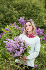 Beautiful young girl with a bouquet of lilacs in the garden 