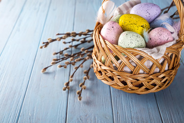 Easter basket filled with colorful eggs on a blue background