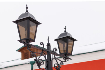 Wrought iron lantern with patterns on the background of the red building and the sky