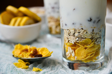 Healthy Breakfast: homemade granola, banana, fresh berries, yogurt in glass cups on light textile background. The concept of healthy eating, high-carbon Breakfast.