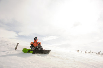 Fototapeta na wymiar Snowboarder sitting on snow in Goderdzi, Georgia