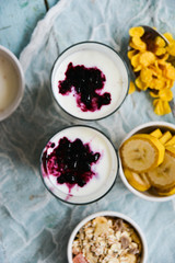 Healthy Breakfast: homemade granola, banana, fresh berries, yogurt in glass cups on light textile background. The concept of healthy eating, high-carbon Breakfast.