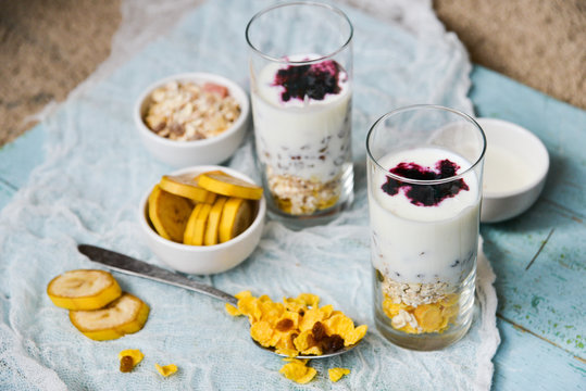 Healthy Breakfast: homemade granola, banana, fresh berries, yogurt in glass cups on light textile background. The concept of healthy eating, high-carbon Breakfast.