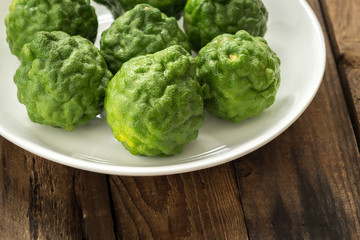 Kaffir lime or lime with white plate on wood


