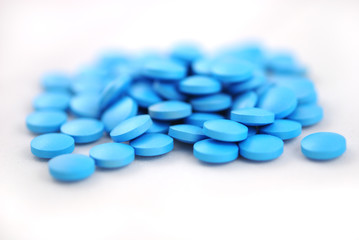 Bright blue round tablets closeup on white background