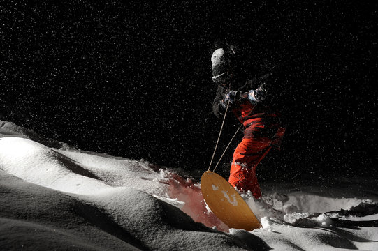 Snowboarder riding on board at night under the snow