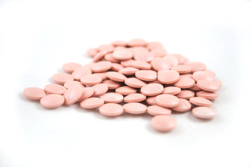 Light pink tablets closeup on white background