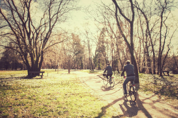 couple is cycling at the park vintage effect, two adults are riding a bicycle 