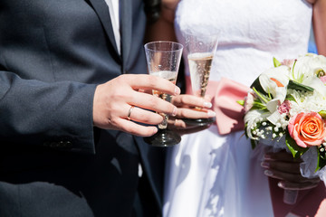Bride and groom hold glasses with champagne