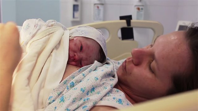 a newborn baby lies on the breast of a happy mother in the hospital. The first minutes of life.
