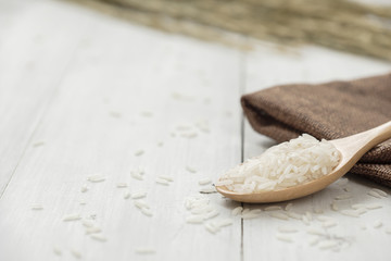 Wooden spoon filled with rice placed on wooden background.
