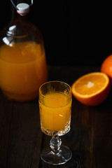 Fresh orange juice in crystal glass with fresh fruits on dark wood table