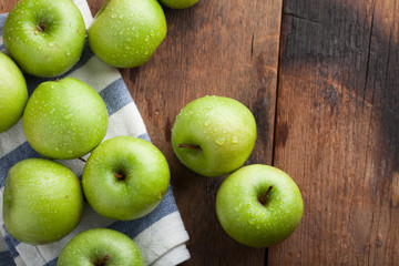 Ripe green apples in a wooden bowl on an old rustic table. Useful fruits on wooden background. Top view with copy space