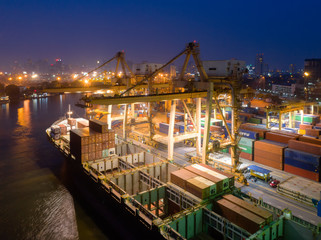 Containers yard in port congestion with ship vessels are loading and discharging operations of the transportation in international port.Shot from drone.