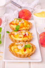 Tartlets with custard, fresh peaches and almonds
