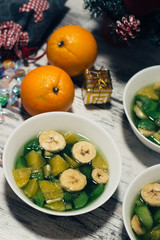 Fruit jelly with fresh banana, kiwi and orange. Wooden rustic background. Top view.