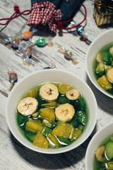 Fruit jelly with fresh banana, kiwi and orange. Wooden rustic background. Top view.