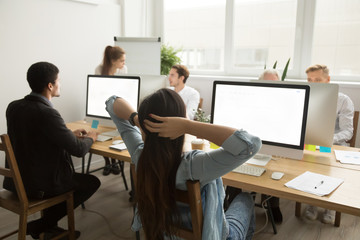 Rear view at female employee relaxing stretching at workplace holding hands behind head, businesswoman or manager resting after finishing computer work taking break in office with colleagues