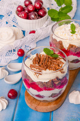 English trifle with chocolate biscuit, whipped cream, cherry and meringue in glass