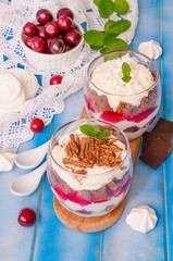 English trifle with chocolate biscuit, whipped cream, cherry and meringue in glass