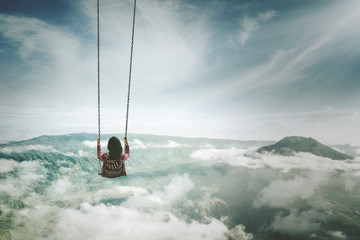 Young woman playing with swing above mountain - obrazy, fototapety, plakaty