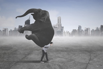 Young businessman carrying an elephant