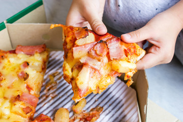 Closeup girl hands picking pizza in paper box. Take away package. Favorite fast food.