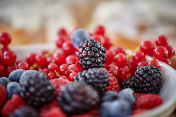 Blueberry, raspberry and blackberry mix background inwhite bowl, table, glasses, harvest!