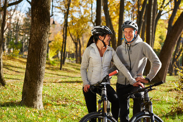 Happy young couple going for a bike ride on an autumn day in the park.